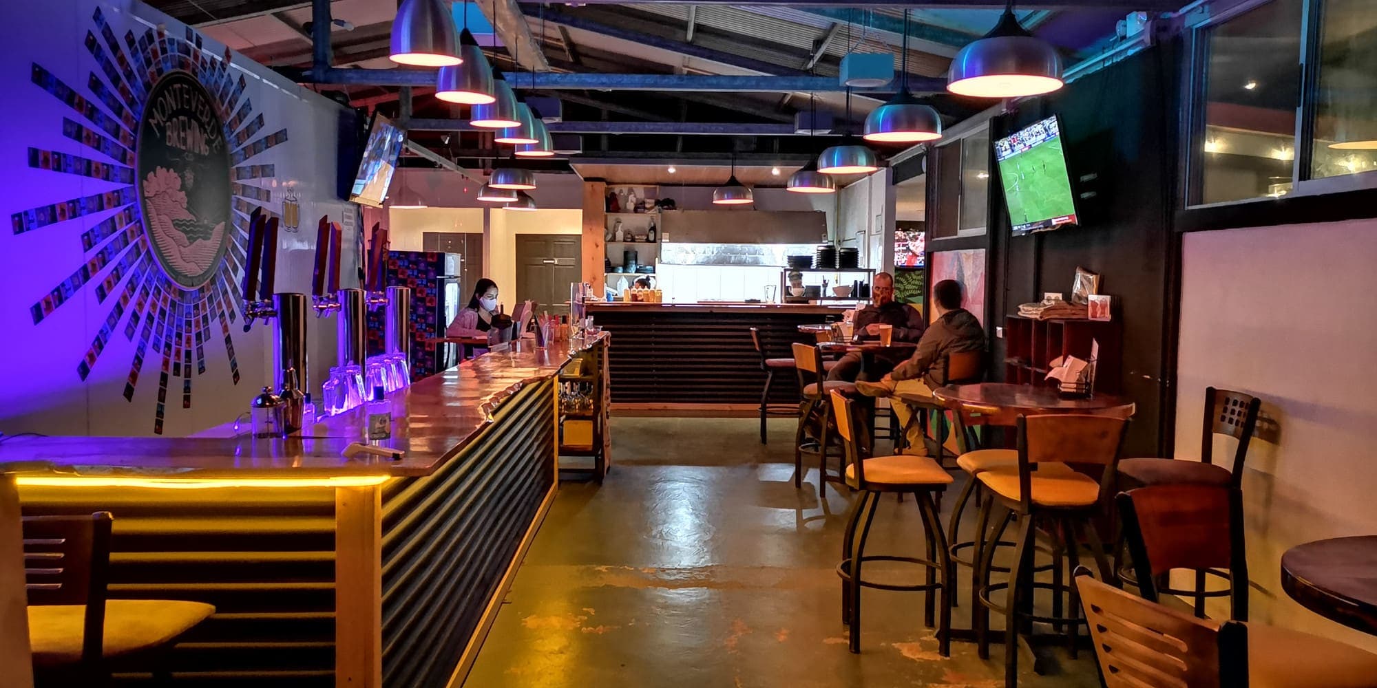 El salón del brewpub de Monteverde Brewing Company: la barra iluminada y las mesas altas
