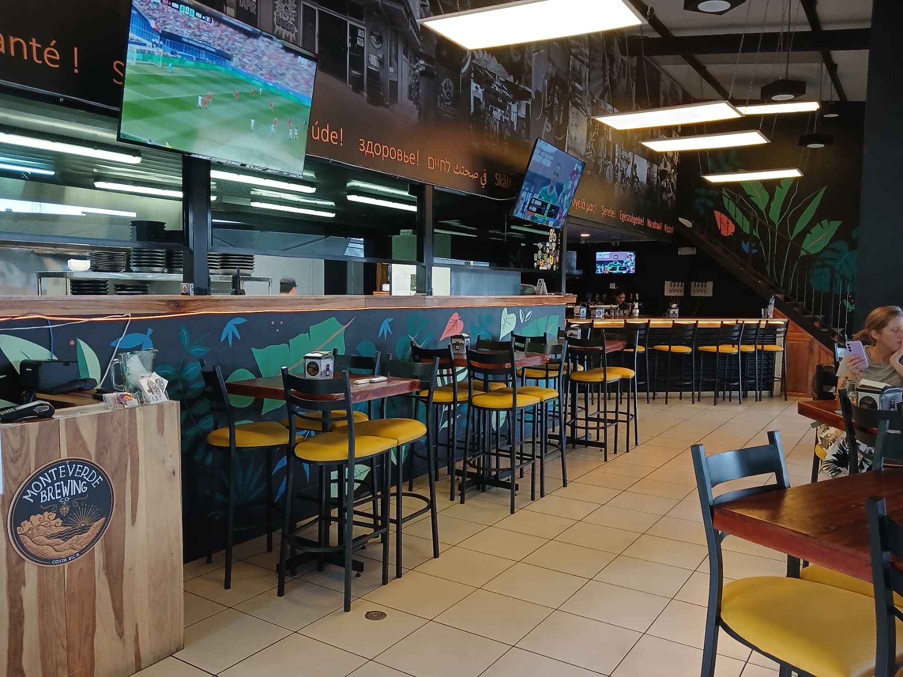 El salón del taproom de Monteverde Brewing Company en La Fortuna, con la barra y el mural de hojas